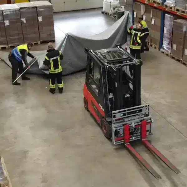 Utilisation du site couverture anti-feu sur un chariot élévateur électrique dans un entrepôt par les pompiers.