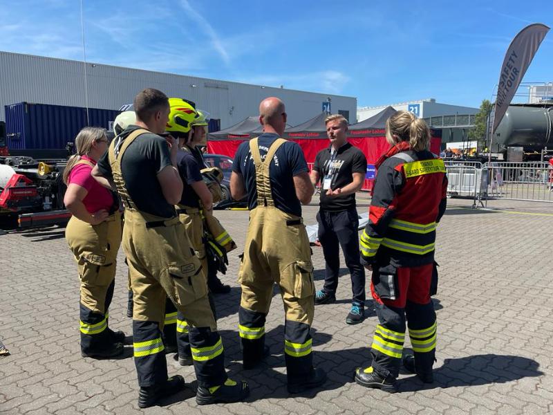 Interschutz Safety Tour - Gruppe von Feuerwehrleuten lauscht Jonas Schwender bei der Erklärung der VLITEX Brandbegrenzungsdecke